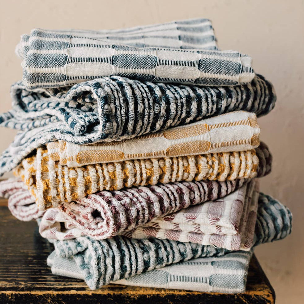 Stack of folded towels on a wooden surface with a beige wall background