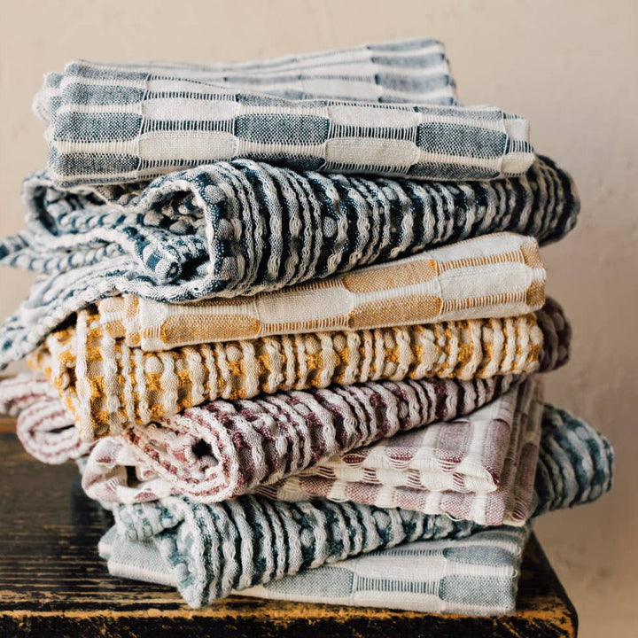 Stack of folded towels on a wooden surface with a beige wall background